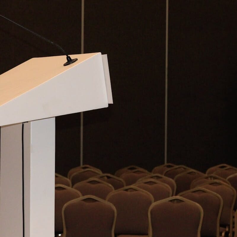 An empty conference room setup with podium and rows of chairs, ready for an event.
